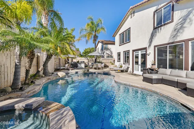 a view of pool with lawn chairs and plants