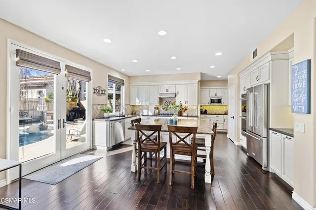 a kitchen with stainless steel appliances wooden floors and dining table