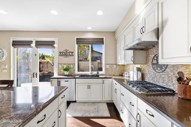 a large kitchen with stainless steel appliances granite countertop a lot of counter space and wooden floor