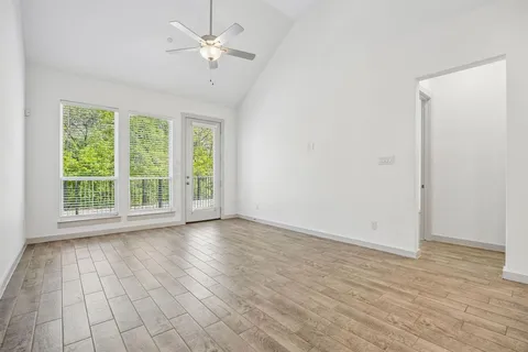 a view of an empty room with a window and wooden floor