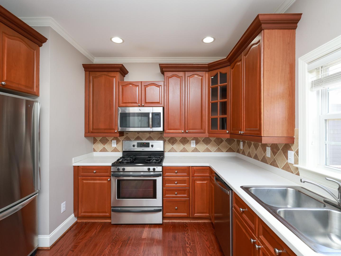 1155 Harp Street Raleigh, NC 27604 - Photo 12 of 33 a kitchen with stainless steel appliances granite countertop a sink a stove a refrigerator cabinets and a wooden floor