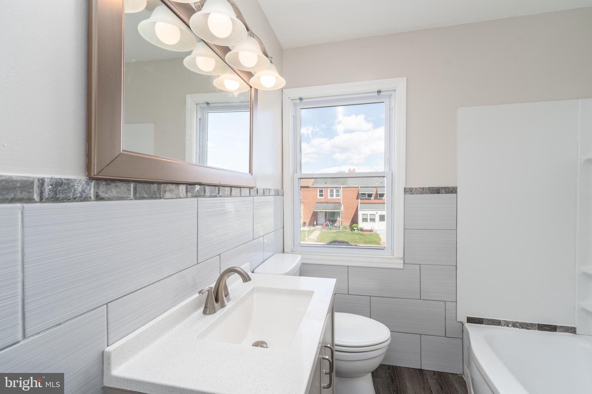 1738 Stokesley Road Baltimore, MD 21222 - Photo 19 of 34 a bathroom with a sink a toilet a mirror and a window