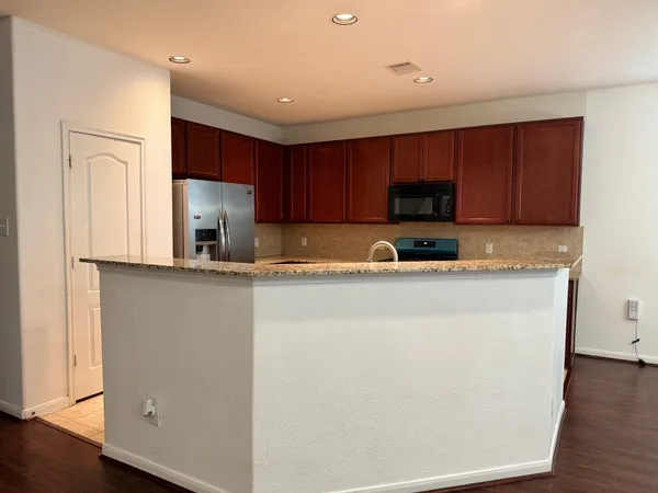 a kitchen with granite countertop a refrigerator sink and cabinets