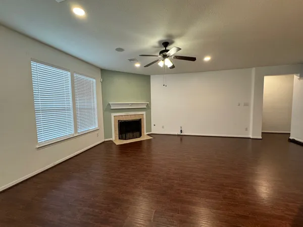 an empty room with wooden floor fireplace and windows
