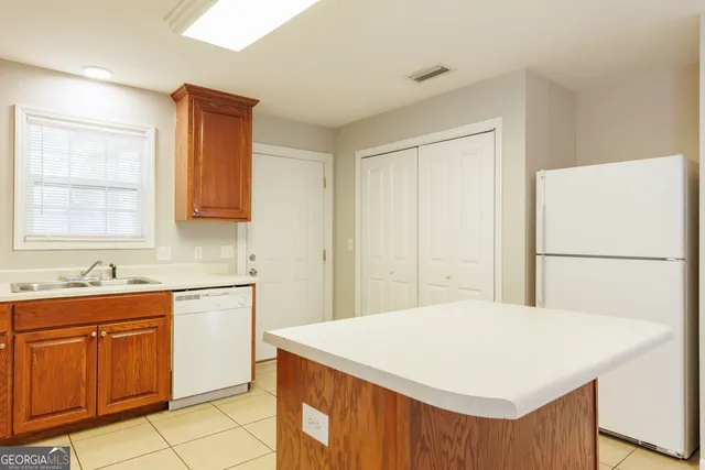 a kitchen with stainless steel appliances a sink a stove a refrigerator cabinets and a window