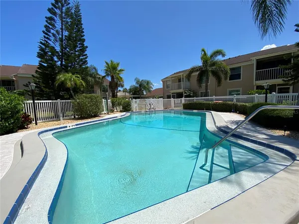 a view of a swimming pool with a lounge chair and palm trees