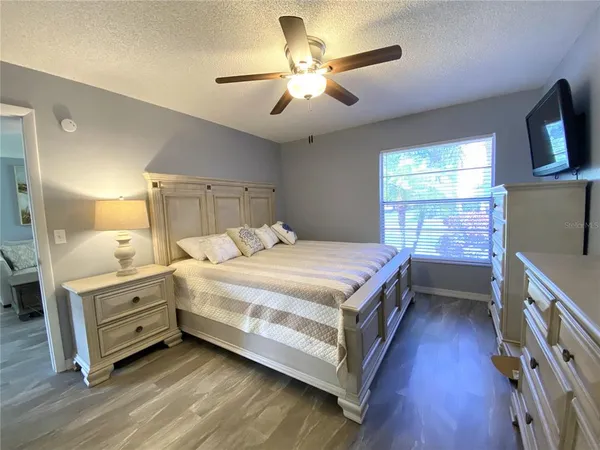 a bedroom with a bed and a flat tv screen on dresser