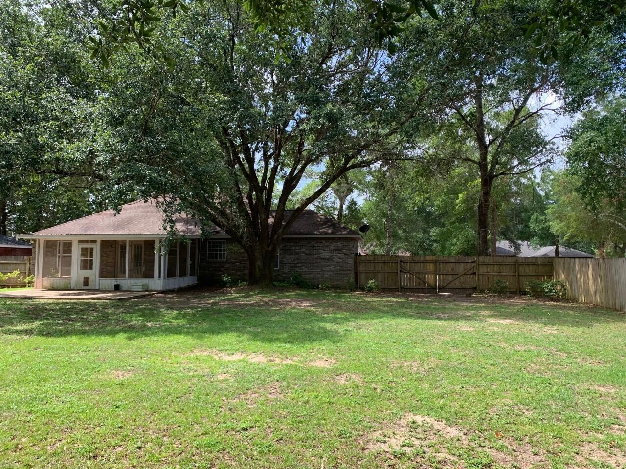 6444 Kylito Circle Crestview, FL 32539 - Photo 23 of 23 a backyard of a house with large trees and wooden fence