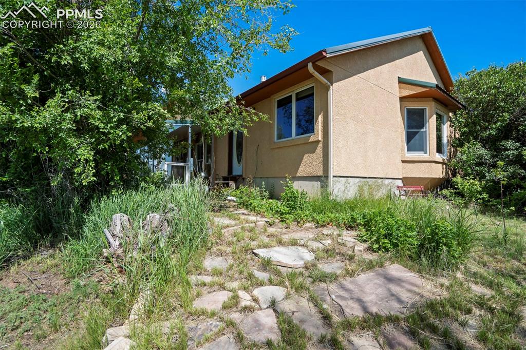 2550 Slocum Road Peyton, CO 80831 - Photo 49 of 50 Stucco exterior featuring a bay window, rain gutters, and an entrance with a covered porch
