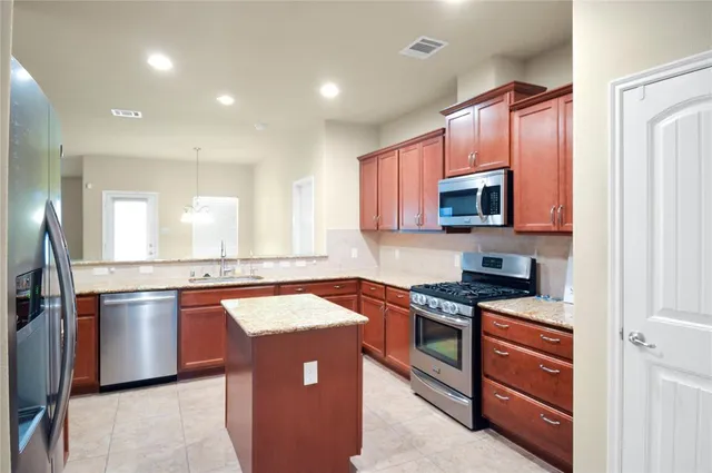 a kitchen with stainless steel appliances granite countertop a sink stove microwave and refrigerator