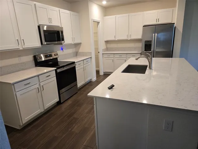 a kitchen with a sink a microwave a refrigerator and cabinets