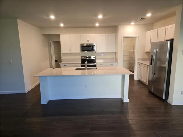 a large kitchen with stainless steel appliances granite countertop a large counter top and wooden floors