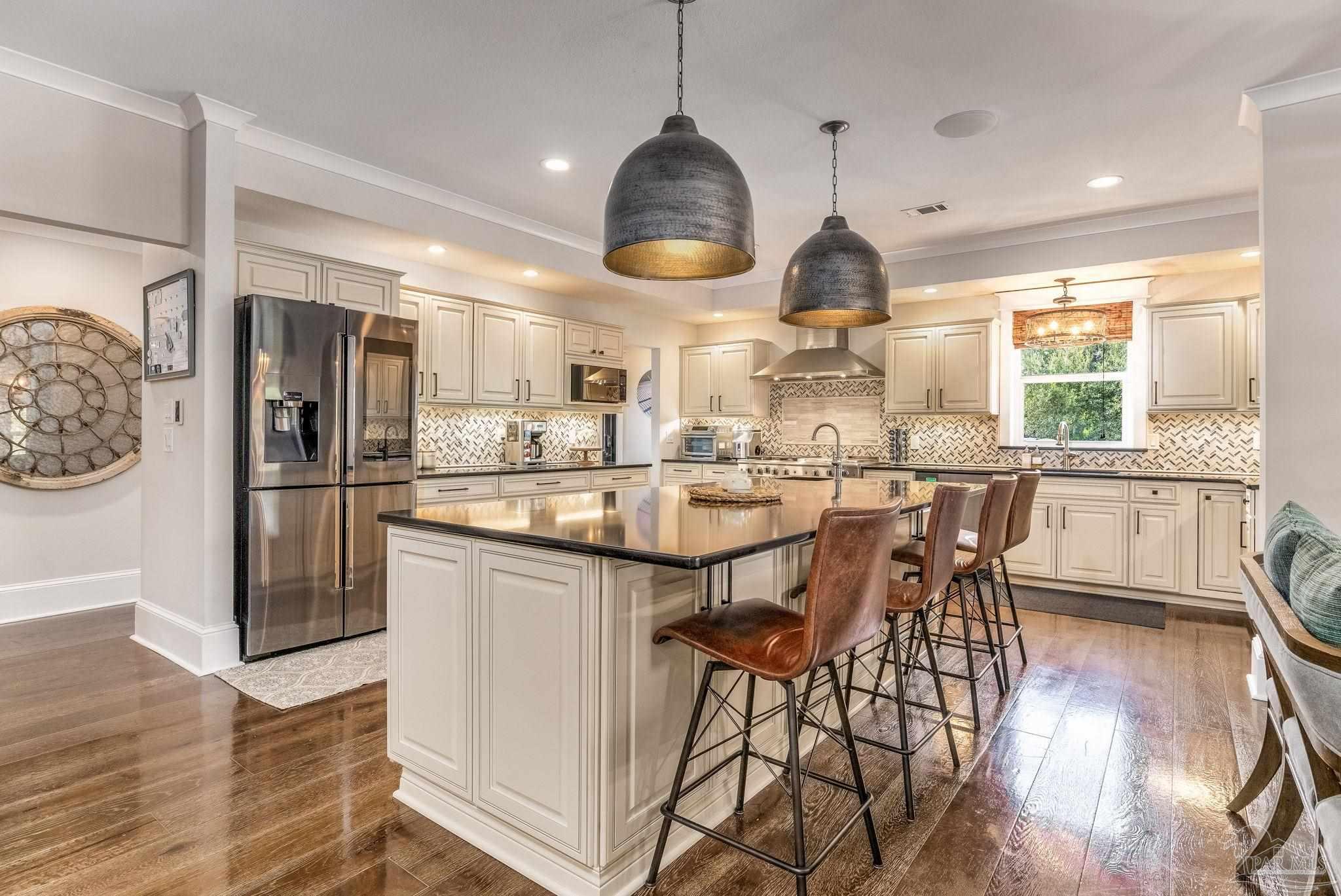 9050 Salter Road Pace, FL 32571 - Photo 3 of 66 a kitchen with stainless steel appliances granite countertop a refrigerator a sink dishwasher a dining table and chairs with wooden floor