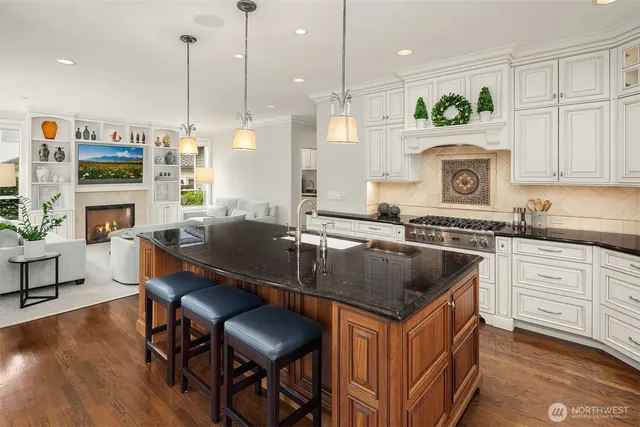 a kitchen with kitchen island granite countertop a sink a stove and a wooden floors
