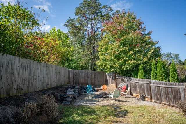 a view of backyard with wooden fence and trees