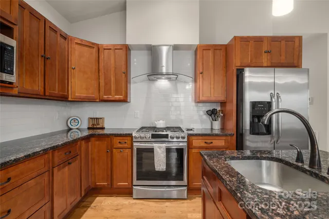 a kitchen with granite countertop a sink stainless steel appliances and cabinets