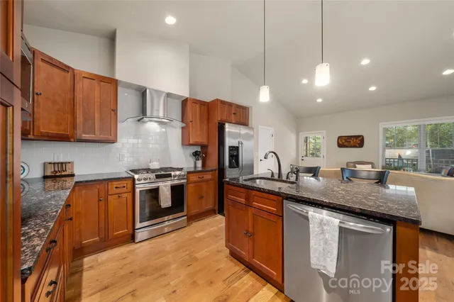 a kitchen with stainless steel appliances granite countertop a sink a stove and a refrigerator