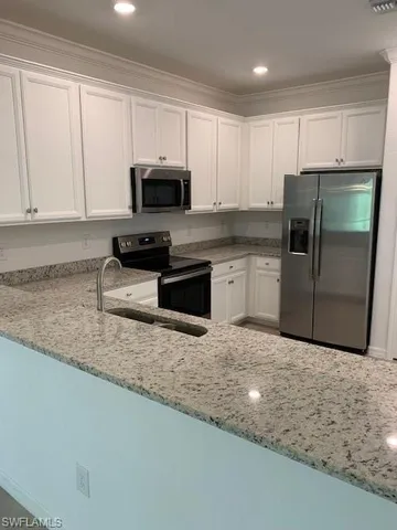 a kitchen with granite countertop a refrigerator sink and cabinets