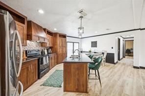 7466 County Road 573 Blue Ridge, TX 75424 - Photo 6 of 25 a kitchen with stainless steel appliances granite countertop a refrigerator a sink dishwasher a stove and a dining table with wooden floor