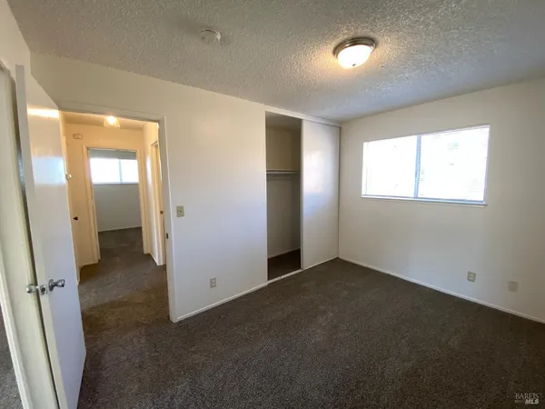 an empty room with closet and windows