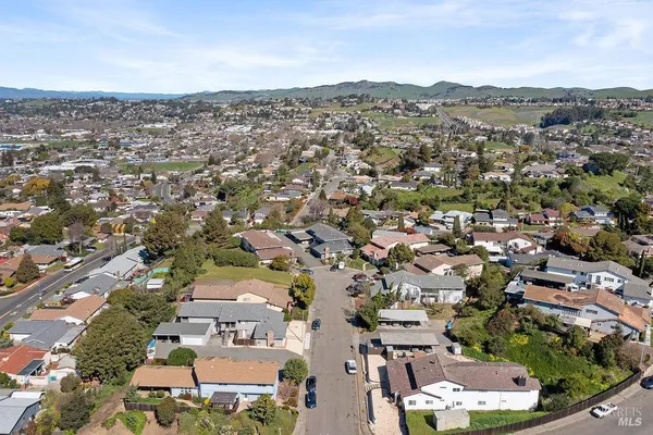 an aerial view of a city with lots of residential buildings and ocean view in back