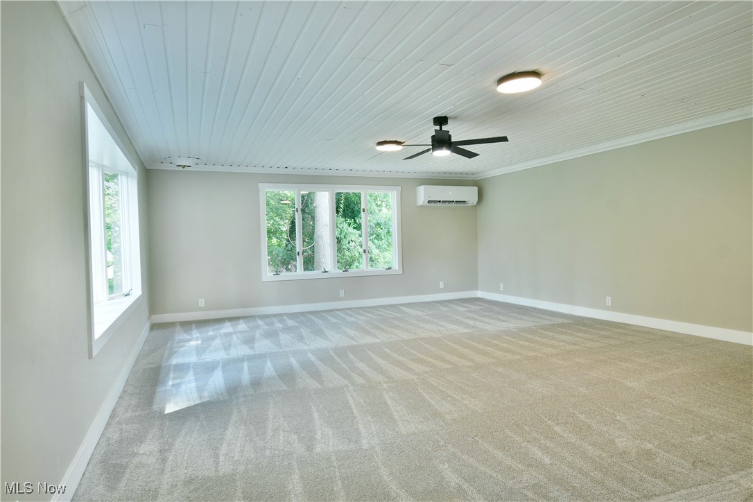 7655 Connelly Road Masury, OH 44438 - Photo 30 of 46 Empty room featuring light carpet, a ceiling fan, a wall mounted AC, crown molding, and wood ceiling