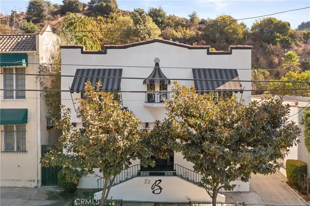 a view of a white house next to a yard with plants