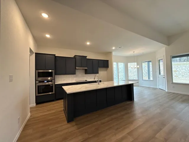a large kitchen with kitchen island a sink wooden floor and outdoor space