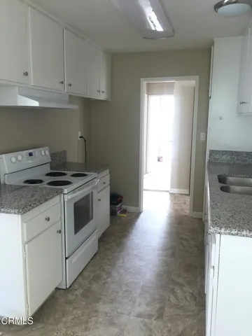 a kitchen with granite countertop white cabinets and white appliances