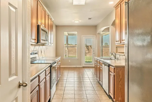 a kitchen with stainless steel appliances granite countertop a sink dishwasher stove and cabinets with wooden floor