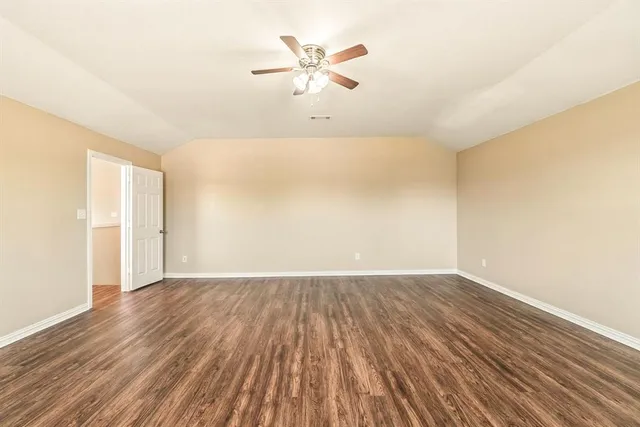 a view of an empty room with window and a kitchen