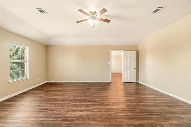 a spacious bedroom with a bed and a flat screen tv