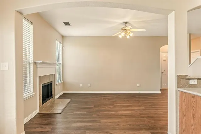 a view of a livingroom with an empty space a fireplace and wooden floor