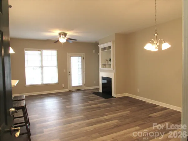 an empty room with wooden floor chandelier and windows