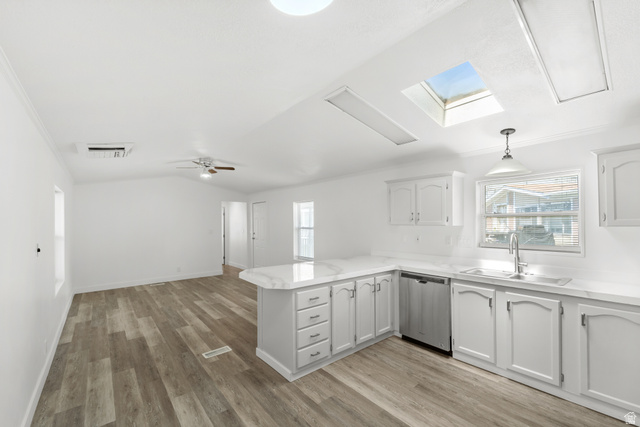 2600 North Hill Field Road, Unit 103A Layton, UT 84041 - Photo 10 of 31 Open-concept living area featuring wood-finish flooring, white cabinetry, a built-in dishwasher, white countertops, and a skylight