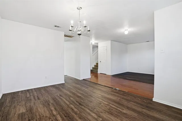 a view of an empty room with wooden floor and a ceiling fan