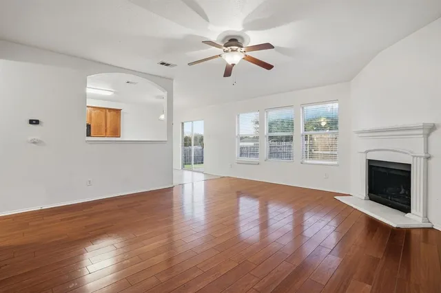 a view of an empty room with wooden floor fireplace and a window