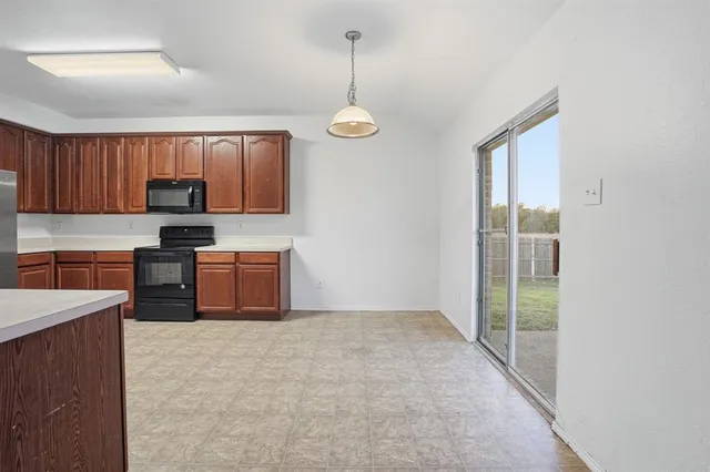 a kitchen with granite countertop a stove a sink and a refrigerator