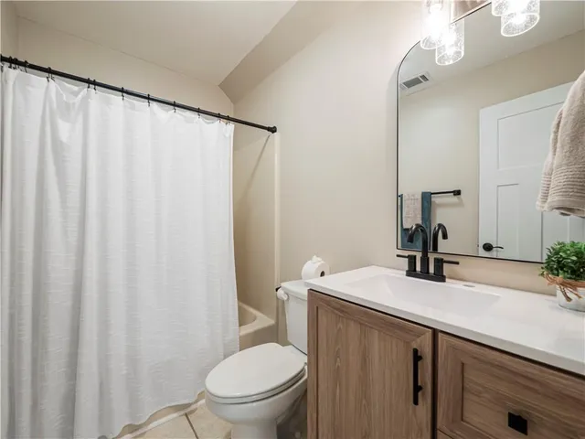 a bathroom with a sink a toilet a mirror and shower curtain