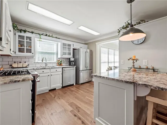 a kitchen with stainless steel appliances granite countertop a sink a stove a refrigerator wooden floor and cabinets