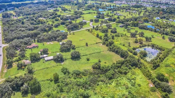 an aerial view of residential houses with outdoor space and trees all around