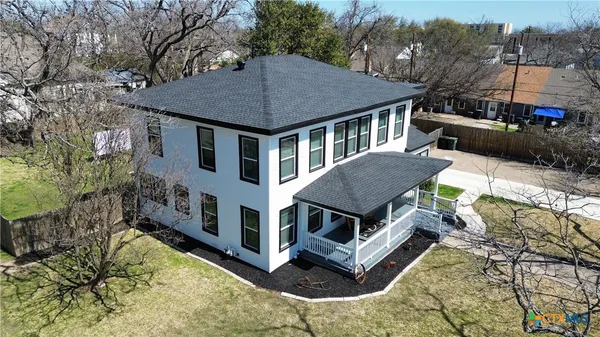 a aerial view of a house with yard and trees in the background