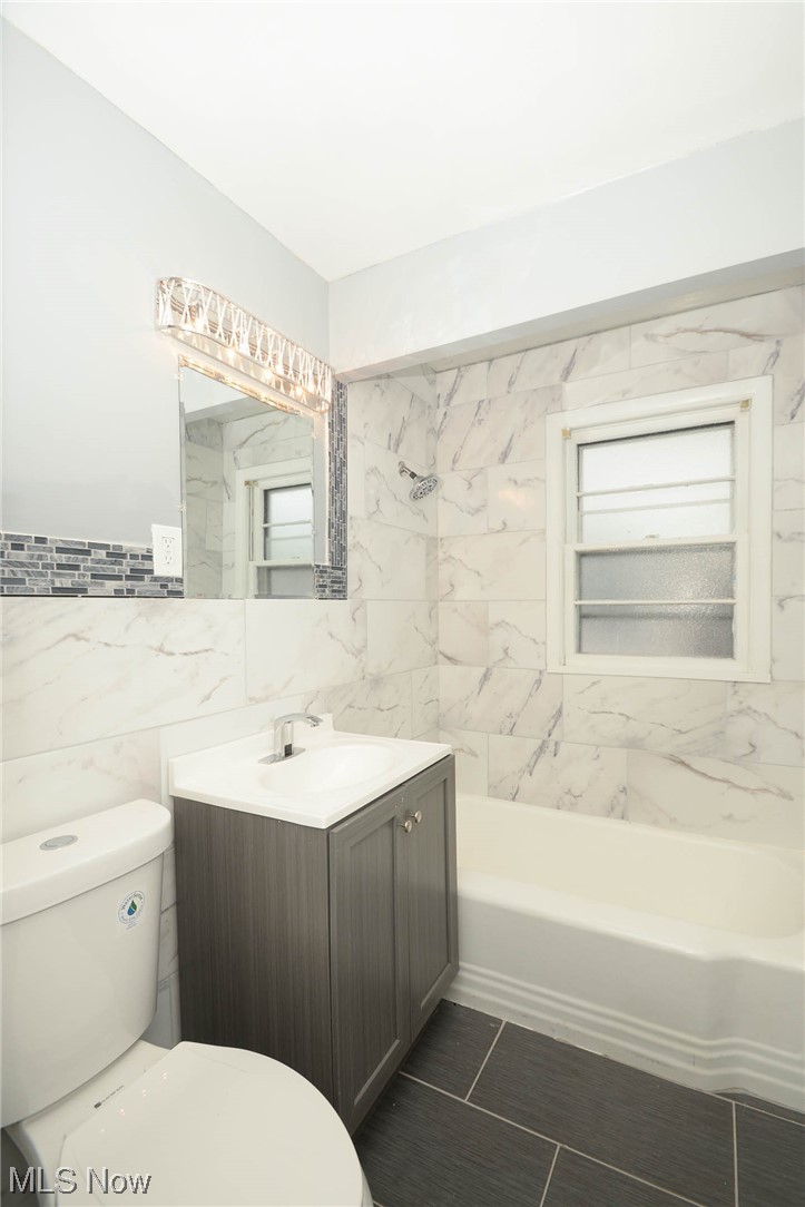 24599 Chardon Road Cleveland, OH 44143 - Photo 19 of 28 Full bathroom with tile walls, vanity, toilet, and tub / shower combination