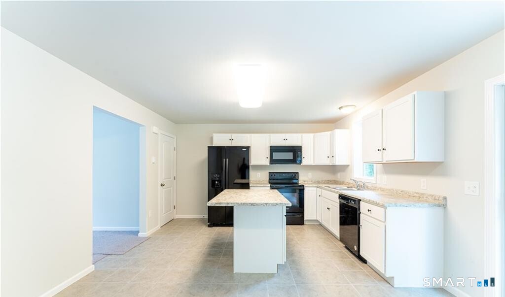 152 Grove Avenue, Unit B Groton, CT 06340 - Photo 5 of 17 a kitchen with kitchen island a stove a sink and white cabinets