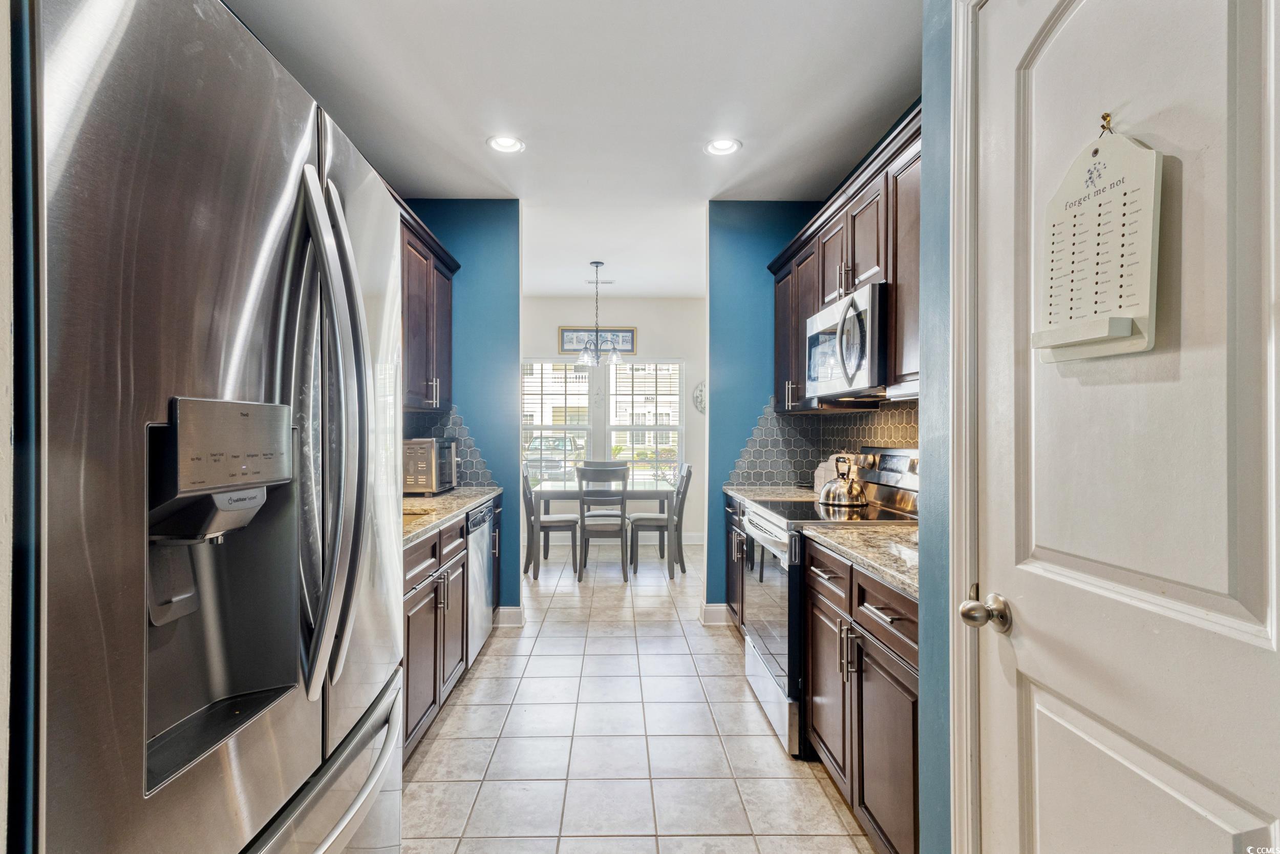 1745 Low Country Place, Unit D Columbia, SC 29209 - Photo 13 of 38 Kitchen with appliances with stainless steel finishes, light tile patterned flooring, decorative backsplash, light stone countertops, and hanging light fixtures