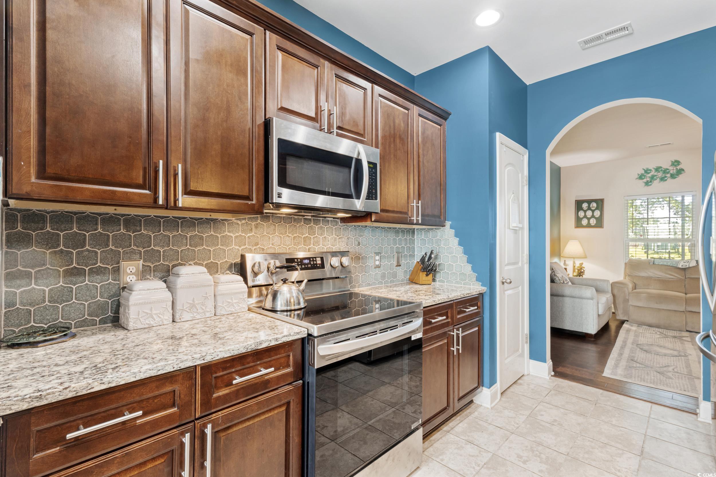 1745 Low Country Place, Unit D Columbia, SC 29209 - Photo 15 of 38 Kitchen featuring appliances with stainless steel finishes, arched walkways, tasteful backsplash, light stone counters, and light tile patterned floors