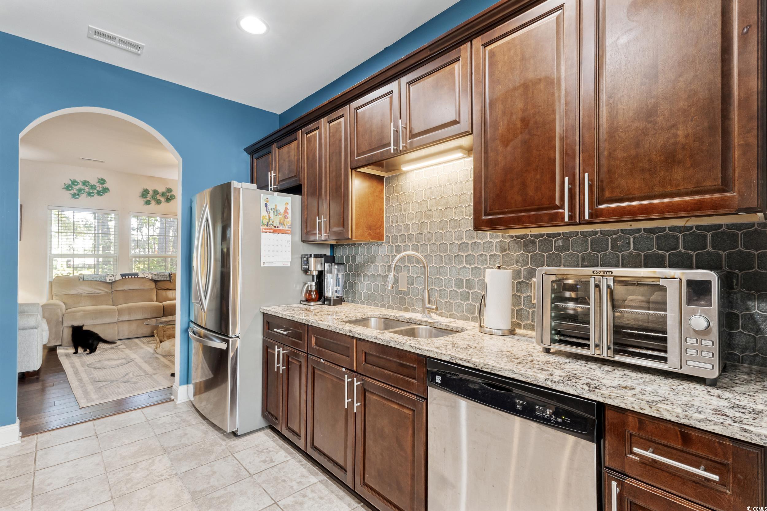 1745 Low Country Place, Unit D Columbia, SC 29209 - Photo 16 of 38 Kitchen featuring appliances with stainless steel finishes, tasteful backsplash, arched walkways, light stone counters, and light tile patterned flooring