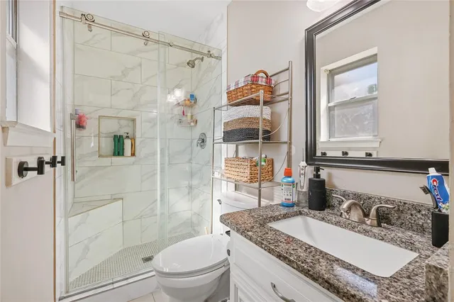 a bathroom with a granite countertop sink toilet and shower