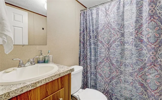 a bathroom with a granite countertop sink and a toilet