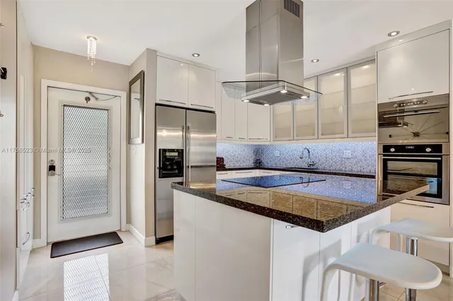 a kitchen with kitchen island a counter top space a sink stainless steel appliances and cabinets